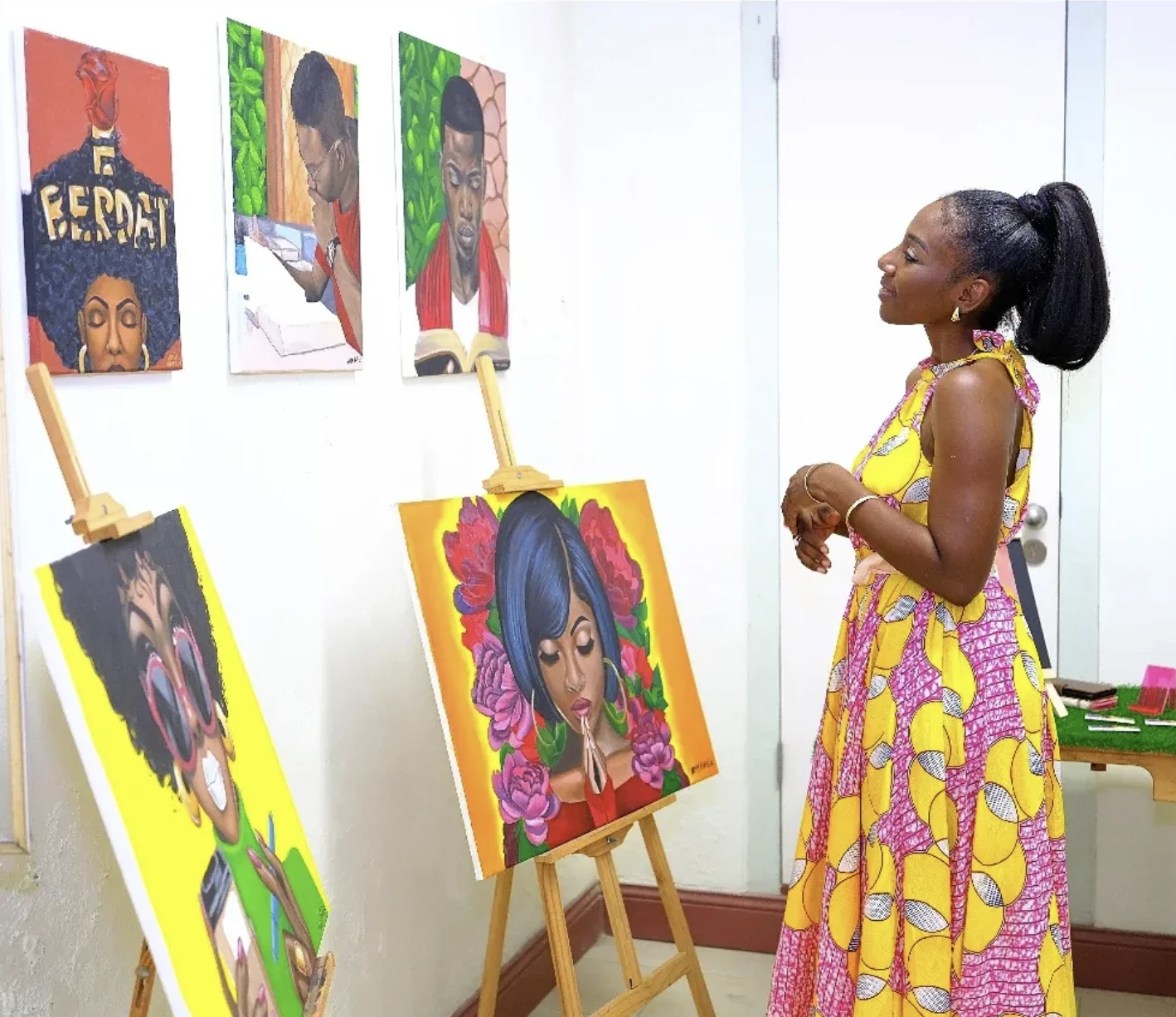 Æmy looking at her canvases on easels at an exhibition