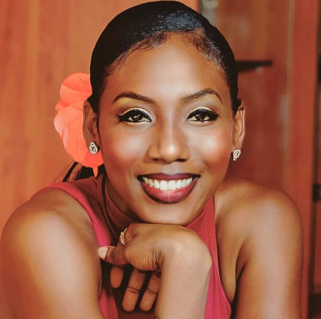 Æmy Niafeliz, chin resting on her hand, a coral flower in her hair